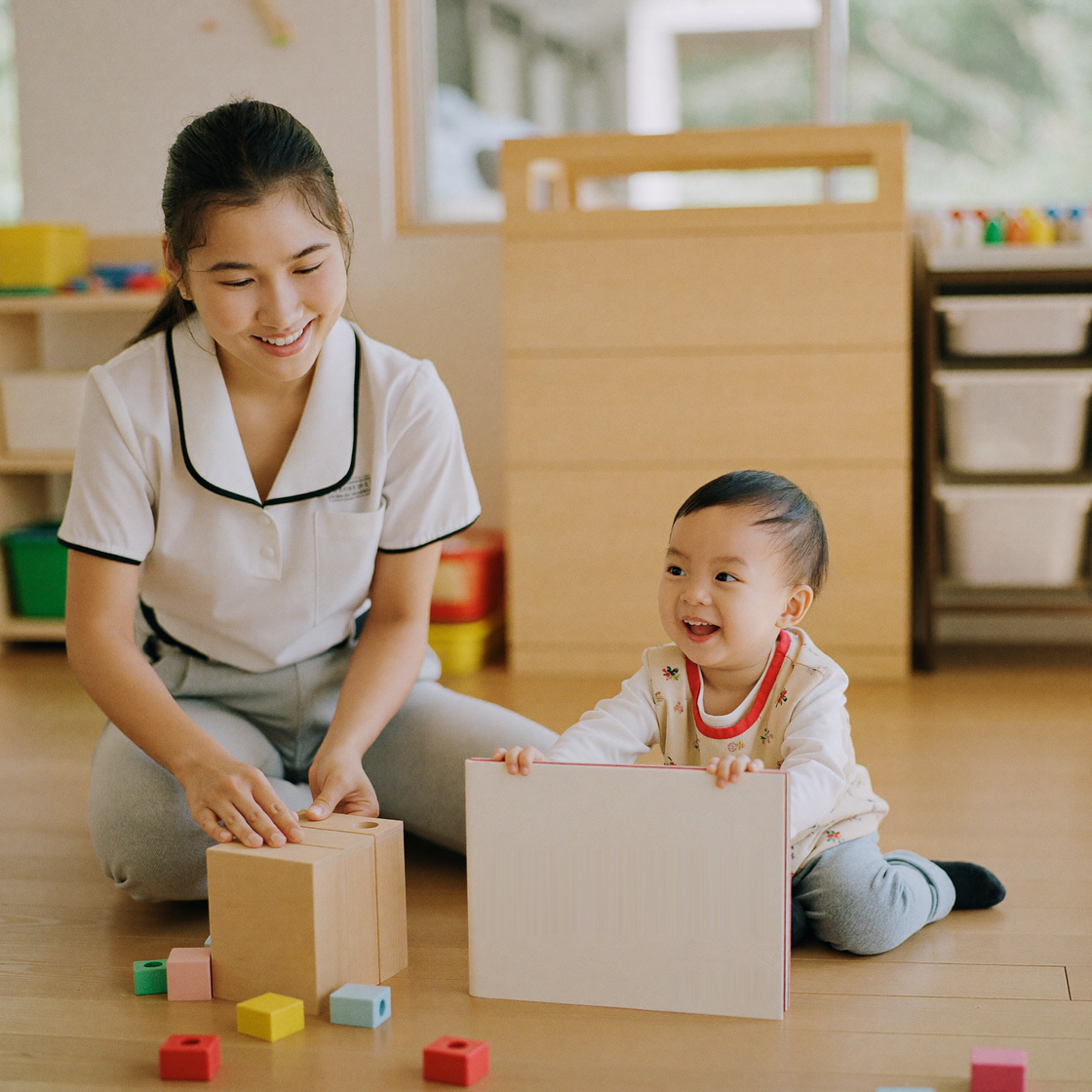 保育士が子どもと積み木や絵本で遊ぶ様子